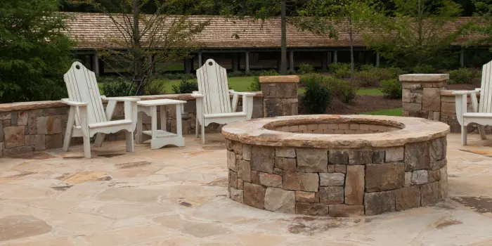 A beautifully designed outdoor patio with a built-in fireplace, cozy seating, and warm lighting creating an inviting atmosphere.